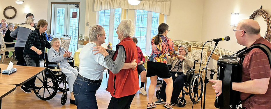 Seniors celebrating Volunteer Appreciation Day with accordion music and dancing.